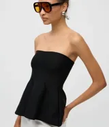 Blusa negra sin breteles, confeccionada en tejido de punto, con diseño ajustado en el busto y detalle de peplum en el ruedo que aporta volumen y movimiento.