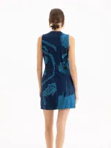 Vestido corto de denim azul con estampa cyanotype de efecto deslavado, sin mangas, escote redondo y cierre frontal completo de metal. Cuenta con corte en la cintura y silueta evasé.
