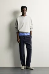 Pantalón negro confeccionado en mezcla de algodón, con cintura elástica, bolsillos frontales y cierre con cremallera y botón.