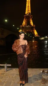 Vestido midi de satén color marrón con estampado a cuadros, escote drapeado y tirantes finos. Presenta un tajo lateral profundo en la falda.