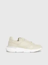 Zapatillas deportivas de mujer Calvin Klein, color beige claro, con cordones y suela gruesa blanca. Presentan una combinación de materiales que incluye piel natural y ecológica, con paneles de malla y detalles de monograma sutil en el lateral.