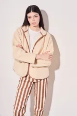 Campera beige de corderito vegano con cuello mao y cierre frontal con botones a presión.