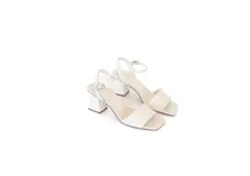 Sandalias de cuero color hueso con taco bloque, tira ancha en la parte delantera y tira ajustable al tobillo con hebilla metálica.