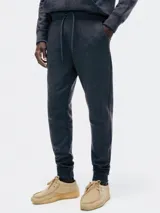 Pantalón tipo babucha de color azul oscuro, confeccionado con interior de felpa. Presenta cintura elástica con cordón de ajuste y puños acanalados en los tobillos.