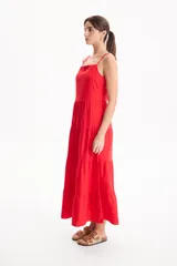 Vestido largo color blanco, confeccionado en lino, con tiras finas regulables, escote recto y falda amplia de corte acampanado con volados escalonados.