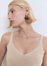 Top de punto fino con acabado metalizado, escote en pico y tirantes finos. Presenta un diseño recto y sencillo, ideal para diversas ocasiones.