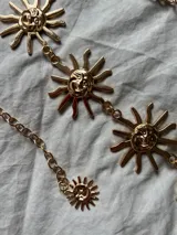 Cadena dorada para la cintura con dijes de soles con cara sonriente.