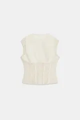 Top de cuello redondo y manga sisa, confeccionado en combinación de tejido liso y encaje. Cuenta con varillas metálicas forradas y cierre frontal con ganchos metálicos.