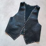 Chaleco de cuero negro con tachas plateadas en el borde.