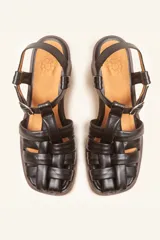 Sandalias de cuero color negro con diseño de tiras cruzadas tipo huarache, tira ajustable con hebilla metálica en el empeine y taco cilíndrico de madera.