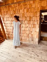 Vestido tejido color gris con hilado levemente brillante, corte oversized y flecos en el ruedo.