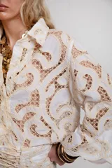Camisa blanca de encaje de guipur con botones ocultos y mangas largas amplias.