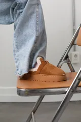 Zueco de gamuza color camel con interior forrado en piel sintética blanca y suela de plataforma plana de goma.