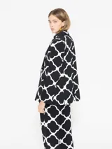 Blazer negro con estampado geométrico blanco, cuello con solapa, acceso con broche y bolsillos plaque.