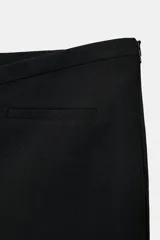 Falda pantalón de tiro bajo en color negro. Presenta falsos bolsillos de vivo en la parte delantera y cierre lateral con cremallera oculta en la costura.