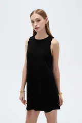 Vestido corto sin mangas en tono beige natural, con cuello redondo y volados delicados en las sisas.
