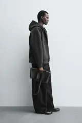 Sudadera con capucha de corte relajado confeccionada en tejido técnico con elasticidad y acabado efecto neopreno. Presenta cierre frontal de cremallera de doble dirección, bolsillos tipo canguro y terminaciones en rib.