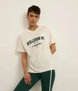 Remera deportiva oversized de algodón blanco marfil, con cuello en V, mangas cortas y estampa frontal verde con la inscripción "Wellness St. Arizona".