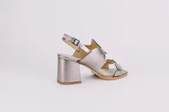 Sandalias doradas de cuero con taco cuadrado y diseño de ondas en el empeine y en la puntera. Cierre con hebilla en el tobillo.