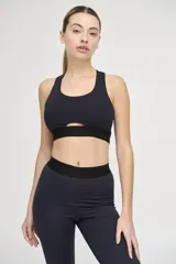 Top deportivo negro con escote redondo, espalda deportiva y abertura geométrica en el centro del pecho.