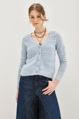 Cardigan de punto calado en color celeste, con cuello en V y cierre frontal de botones. Presenta un diseño de textura suave con mangas largas y corte ajustado.