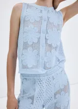 Chaleco celeste de punto con diseño de flores perforadas, sin mangas, escote redondo y cierre frontal con botones.