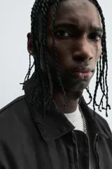 Cazadora de algodón color negro lavado, de corte relajado (relaxed fit), con cuello solapa a contraste, cierre frontal de cremallera, bolsillos canguro en la cadera y puños con botón a presión.