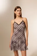 Vestido corto con estampado a cuadros en tonos lila y gris, con breteles finos, escote en V con detalle de encaje negro y falda con volantes.