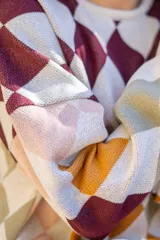 Sweater tejido de algodón con diseño de rombos multicolor en tonos marrones, azul y rojo. Presenta una silueta oversize, cuello redondo y mangas largas abullonadas con puños ajustados.