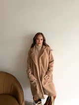 Tapado de textura tipo peluche, color camel, con solapas clásicas, cierre frontal de botones y bolsillos laterales.