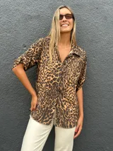 Camisa de manga corta con estampado animal print, cuello clásico y cierre frontal con botones. Presenta un corte holgado y fluido.