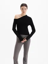 Top de tejido de punto color negro, con diseño al cuerpo, hombros descubiertos y mangas largas.