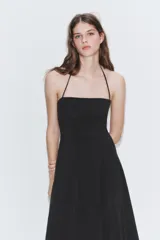 Vestido largo de color negro con cuello halter y escote recto. Presenta un diseño fluido con cierre de cremallera oculta en la espalda y lazada ajustable en el cuello.