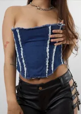 Corset strapless de denim azul con detalles desflecados en los bordes y en las costuras verticales.