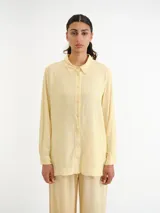 Camisa amarilla de manga larga, con cuello camisero clásico y cierre frontal de botones.