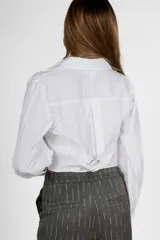 Camisa crop blanca de manga larga con cuello clásico y cierre frontal con botones.