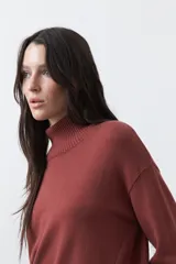 Polera de tejido liviano en color negro, con cuello alto, mangas largas y corte relajado. Presenta un diseño minimalista con recortes laterales que aportan estructura a la prenda.