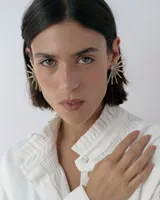 Caravanas tipo ear cuff con diseño de medio sol, compuestas por varillas metálicas plateadas, centro con strass y detalle de resina. Diseño liviano y brillante.