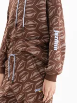 Pantalón jogging marrón con estampado de labios, cintura elástica con cordón ajustable y puños en los tobillos.