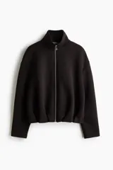 Campera efecto neopreno color negro, con cuello chimenea, cierre frontal completo, hombros caídos y diseño fruncido en el bajo.