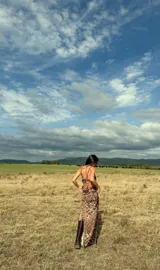 Vestido largo de fiesta con estampado animal print en tonos marrones. Presenta un diseño con breteles trenzados que se cruzan y envuelven el cuerpo, con una caída fluida y elegante.