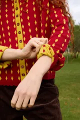 Cardigan reversible de punto con estampado de rombos pequeños, cuello alto y cierre frontal completo con botones. Presenta detalles de ribetes en color contrastante en cuello, puños y cartera de botones.
