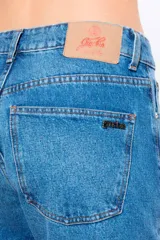 Jean recto de denim negro con tiro medio y largo al tobillo. Presenta ruedo desflecado y avíos personalizados Ginebra en níquel.
