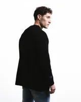 Sweater negro de punto con cuello redondo y corte holgado. Diseño con motivo de zurcido en la manga izquierda.