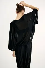 Top negro de punto transparente, con corte holgado, mangas murciélago tres cuartos, escote redondo y bajo recto.