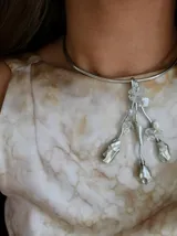 Gargantilla rígida plateada con colgante de nácar y metal plateado con forma de flores y hojas.