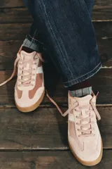 Zapatillas deportivas de estilo retro, confeccionadas en una combinación de gamuza en tonos rosados y detalles en cuero sintético blanco. Presentan cierre mediante cordones al tono y suela de goma plana en color caramelo.