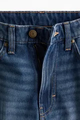 Jean de tiro alto confeccionado en denim rígido, con diseño de cinco bolsillos, cierre con botón y corte de pierna recta levemente holgado.