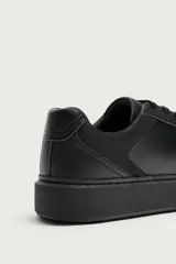 Zapatilla deportiva monocolor de diseño minimalista, con cordones y suela de plataforma con volumen.