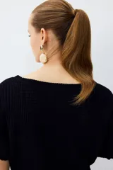Top en punto negro con textura, escote bote y mangas murciélago cortas.
